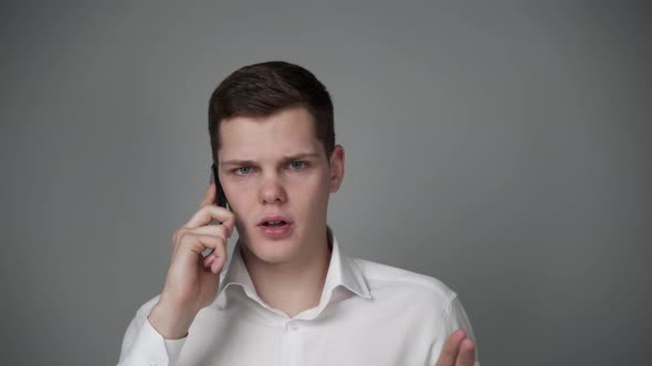 A Young Guy in a White Shirt Emotionally Talking on the Phone