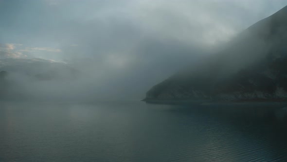 Aerial shoot. drone flies thought the fog over the lake on sunrise