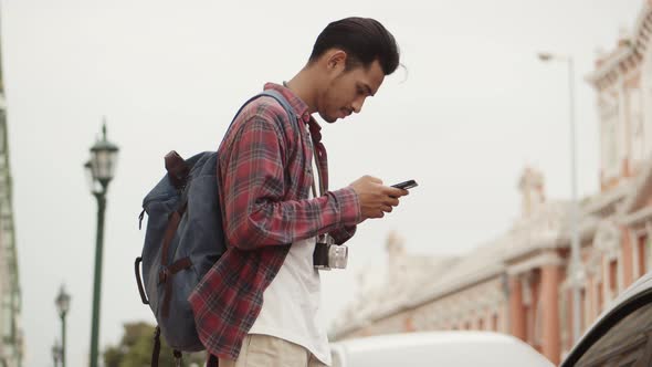 Tourists Asian man using a smartphone checking map while standing beside the street.