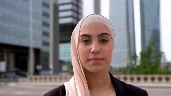 Young arabian business woman smiling on camera with city in the background