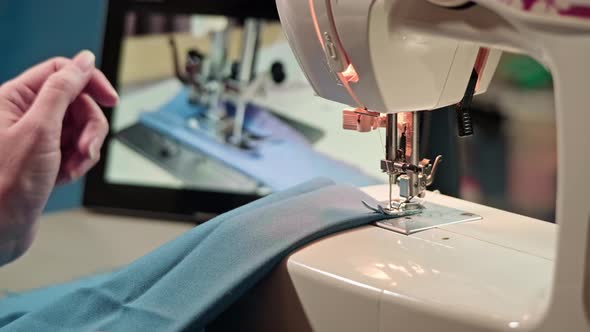 The process of learning to sew online. On the sewing machine and the hands of a woman.