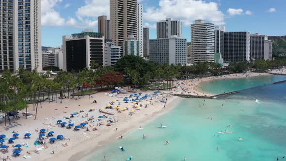 Aerial close-up shot flying over bustling Waikiki Beach on the island of O'ahu, Hawaii. 4K alt
