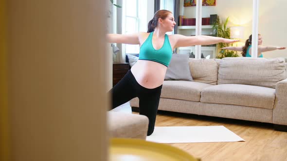 Pregnant woman practicing yoga in living room alt