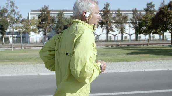 Active Male Pensioner with Hearing Aid Device Jogging Outside alt