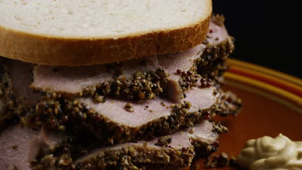 Rotating shot of delicious, premium pastrami sandwich next to a dollop of dijon mustard alt
