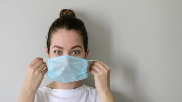 Portrait of Girl Is Putting on Mask in Coronavirus Pandemic on Grey Background.