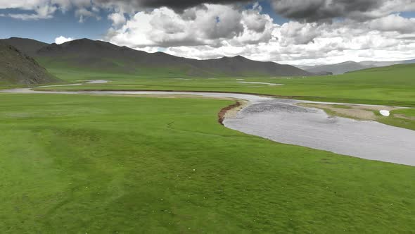 River Flowing Through an Empty Green Meadow with Unmanned and Treeless alt