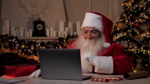 Thoughtful Modern Santa Claus Uses Laptop Buys Christmas Gifts on Internet alt