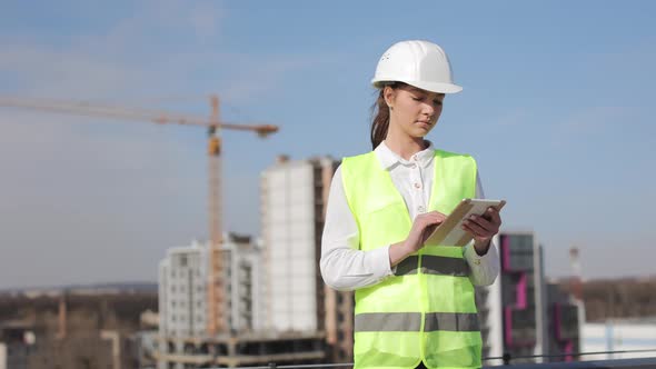 Portrait of Young Woman Engineer Who is Working on the Tablet alt
