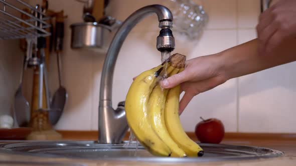 Woman Hands Turns on a Tap Washes Ripe Bananas in Sink Turns Off Water alt