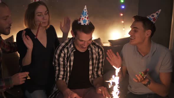 Friends in Colorful Caps Celebrating Birthday Party Surprising Friend with Cake with Burning alt
