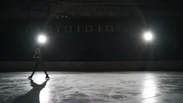 Young Female Figure Skater is Wearing Black Sportswear for Workout is Skating on Ice Rink Alone at alt