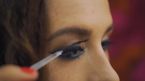 Girl Puts False Eyelashes on the Eye with Tweezers