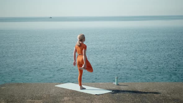 Yoga Woman in Red Sport Costume Doing Asana Near Sea