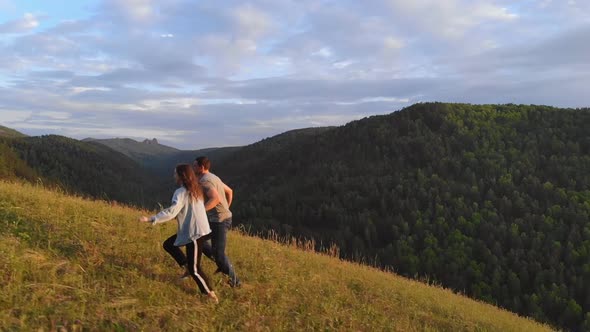 A Young Couple Runs Happily Along a Mountain Path