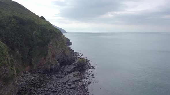 Aerial tracking upwards above the rugged cliffs of Exmoor looking west at the Valley of rocks. Devon alt