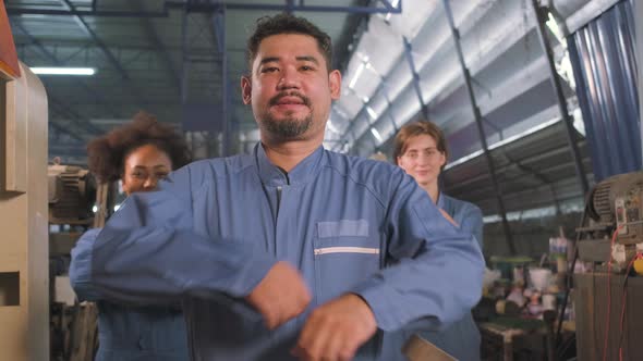 Multiracial workers collaborate and express happy work in a mechanical factory. alt