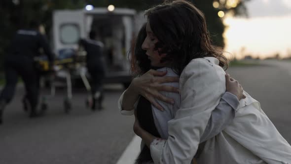 Mother Embracing Daughter While Doctors Helping Father alt