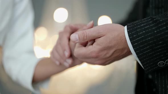 Hands of Newlyweds in Wedding Day Groom is Holding and Stroking Palm of Bride alt