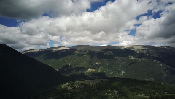 Aerial View of Hillside in Front of Steep Mountains in Abruzzo Italy  Circular Drone Shot alt