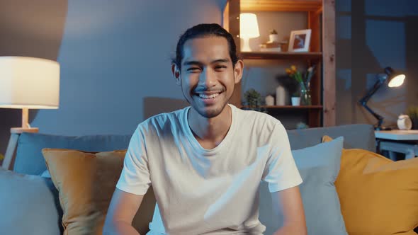 Happy young freelance asian man looking at camera smile and talk with friends on video call.