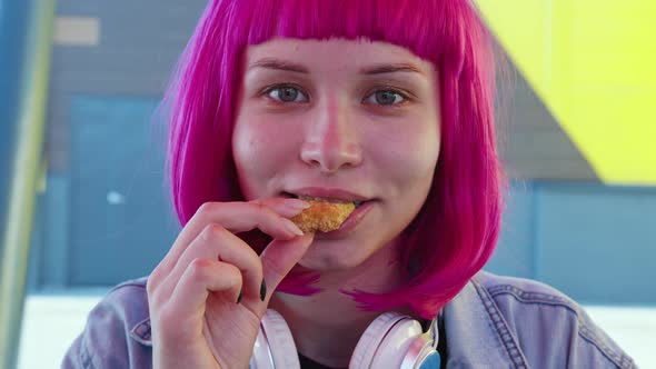A Young Woman with Pink Hair is Eating Fast Food alt
