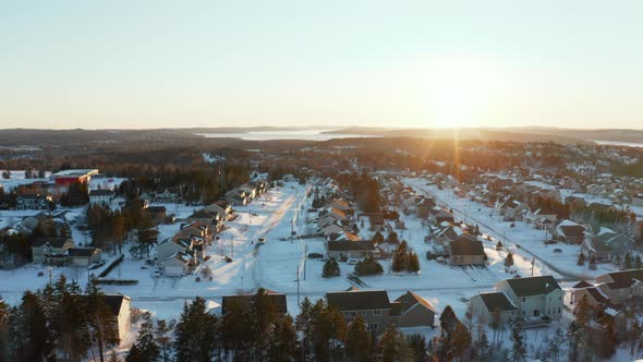 Gorgeous sunset aerial flying over snow covered homes in a residential community on a cold winter ev alt