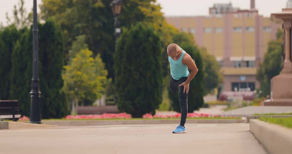 Athlete Warms Up the Muscles of the Legs Training on the Street