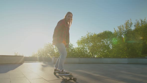 Beautiful Young Female Skater Riding on Longboard at Daybreak alt
