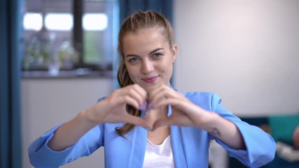 Elegant Charming Caucasian Woman Gesturing Heart Shape with Hands Smiling Looking at Camera alt