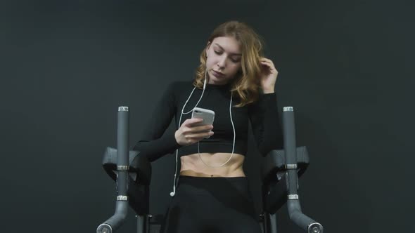 Front View of Attractive Fitness Woman Listens Music and Relaxes After Exercise alt