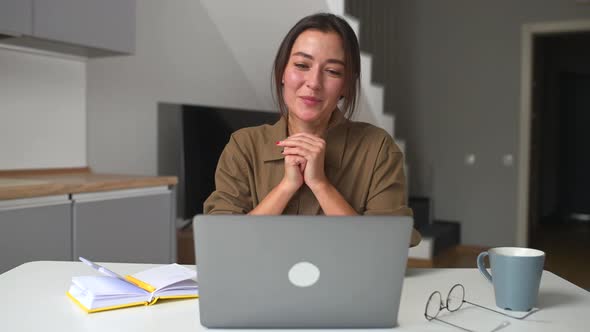 Smiling Asian Businesswoman Taking Notes Sitting at the Desk in Modern Home Office Space