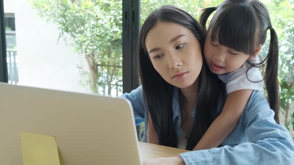 Young Asian dad enjoys teaching his lovely daughter do a homework on a laptop.