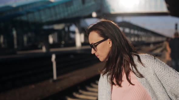 Woman with Glasses in the Last Light of the Sun Awaiting the Arrival of the Train on the Platform of