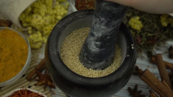 Woman's hand mixes and crushes sesame seeds by granite mortar alt