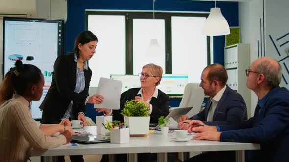 Focused Woman Manager Executive and Multiethnic Team Analyzing Paperwork alt