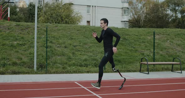 Side View of Disabled Male Sportsman with Amputated Leg with Prosthetic Blade Jogging at Sports alt