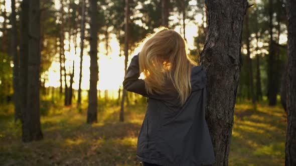 A Tall Woman Standing Near Tree and Touching Her Long Blond Hair on Sunset