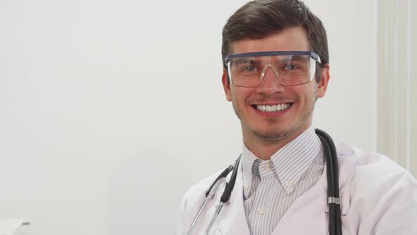 A Smiling Doctor Puts on Special Transparent Laboratory Glasses alt