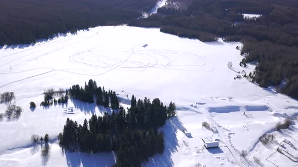 Snowy winter sunny forest near residential small houses alt