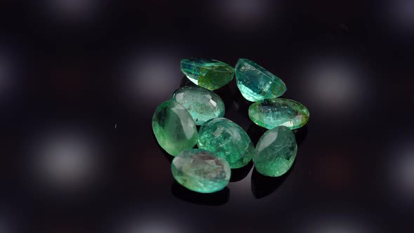 Natural Green Emerald on the Turning Table on the Black Background alt