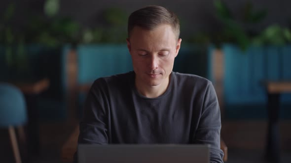 Handsome Freelancer Businessman in Glasses Diligently Working on Laptop in Cafe alt