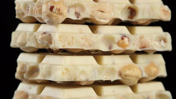 white chocolate with nuts on black background. the frame moves from bottom to top. 4K UHD video alt