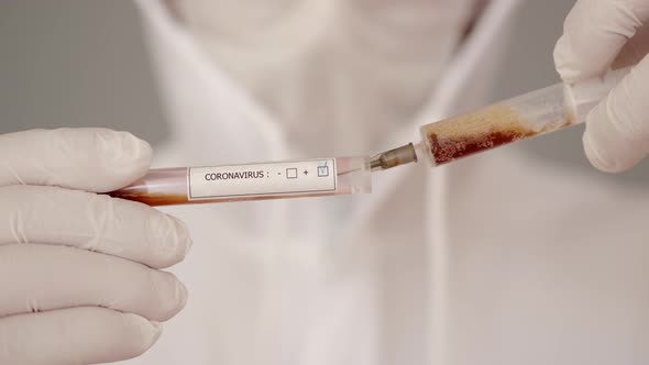 The Scientist in Full-covering Equipment Is Collocting Blodd From a Test with a Syringe alt