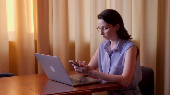 Business Woman in a Shirt and Glasses is Sitting at a Large Desk in the Office and Working on a alt