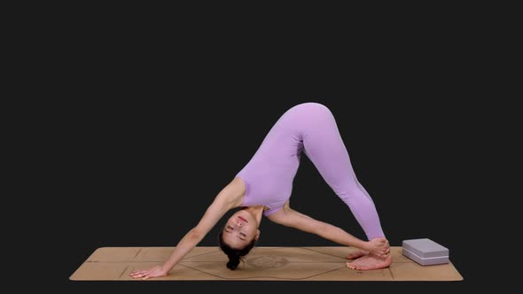 Young Woman Doing Triangle Posture and Downward Facing Dog Pose while Practicing Yoga, Alpha in