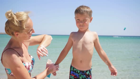 Portrait of a Mother Taking Care of Her Son, a Woman Applying Sunscreen Lotion To the Baby's Skin alt