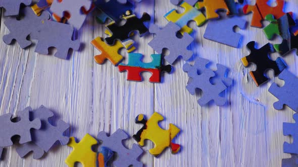 Close-up of the colorful puzzle pieces falling on the wooden background. Slow motion alt