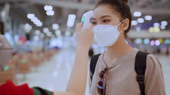 terminal staff check Asian woman body temperature with infrared forehead thermometer