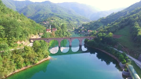 Flying over river and old stone bridge in Bosnia alt